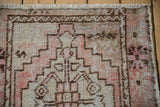 Distressed pile of vintage Oushak rug, showing geometric pattern, foundation wear, and fringe.