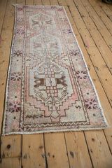 Distressed Oushak rug runner with geometric stepped medallions in soft coral, blue, and brown.