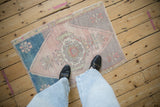 Distressed vintage Oushak rug detail, featuring geometric medallion in blush, mauve, and dusty teal.