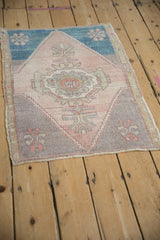 Distressed vintage Oushak rug displaying central medallion and geometric finials in soft pastel shades.