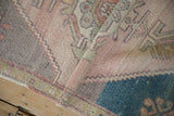Folded vintage distressed Oushak rug revealing soft mauve and teal geometric designs.