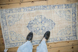 An overhead view showing the scale of a distressed vintage Oushak rug with a blue medallion.