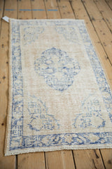A vintage distressed Oushak rug's cream and blue pattern viewed from a high-angle perspective.