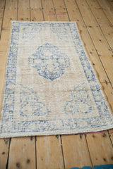 Angled perspective on a vintage distressed Oushak rug, displaying its soft, low-pile texture.