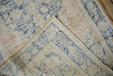Folded corner of a vintage distressed Oushak rug, revealing the woven back and hand-knotted pile.