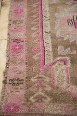 Textured edge of distressed Kars rug, showing vibrant pink and coffee brown geometric motifs.
