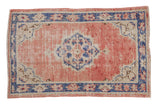 Hand knotted vintage Oushak rug with distressed dusty rose ground and blue scalloped medallion.
