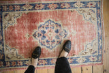 Distressed vintage Oushak rug texture with dusty rose pile and areas of wear.