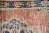 Patinaed dusty rose, denim blue, ivory motifs, and worn texture on a vintage Oushak rug.