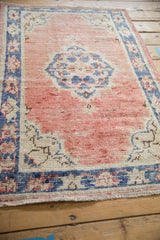 Vintage distressed Oushak rug detail, highlighting worn dusty rose, denim blue, and ivory pile.