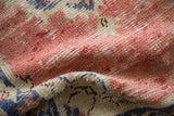 Distressed Oushak rug pile with worn dusty rose, ivory, and denim blue tones.