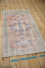 Close-up of distressed vintage Oushak rug with abrashed rose field and blue motifs.