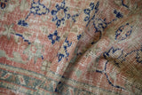Distressed Oushak rug showing worn rose, ivory, and cobalt blue pile texture.