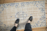 Distressed Oushak rug showcasing worn low pile and faded cream and denim blue florals.