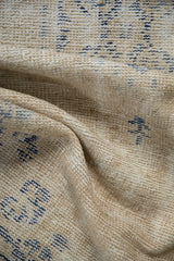 Distressed hand-knotted Oushak rug detail, with worn pile, visible foundation, cream, and faded denim blue.