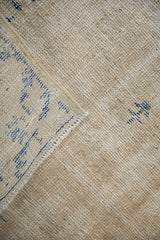 Hand-knotted reverse of a distressed Oushak rug, showing cream foundation and blue pattern.