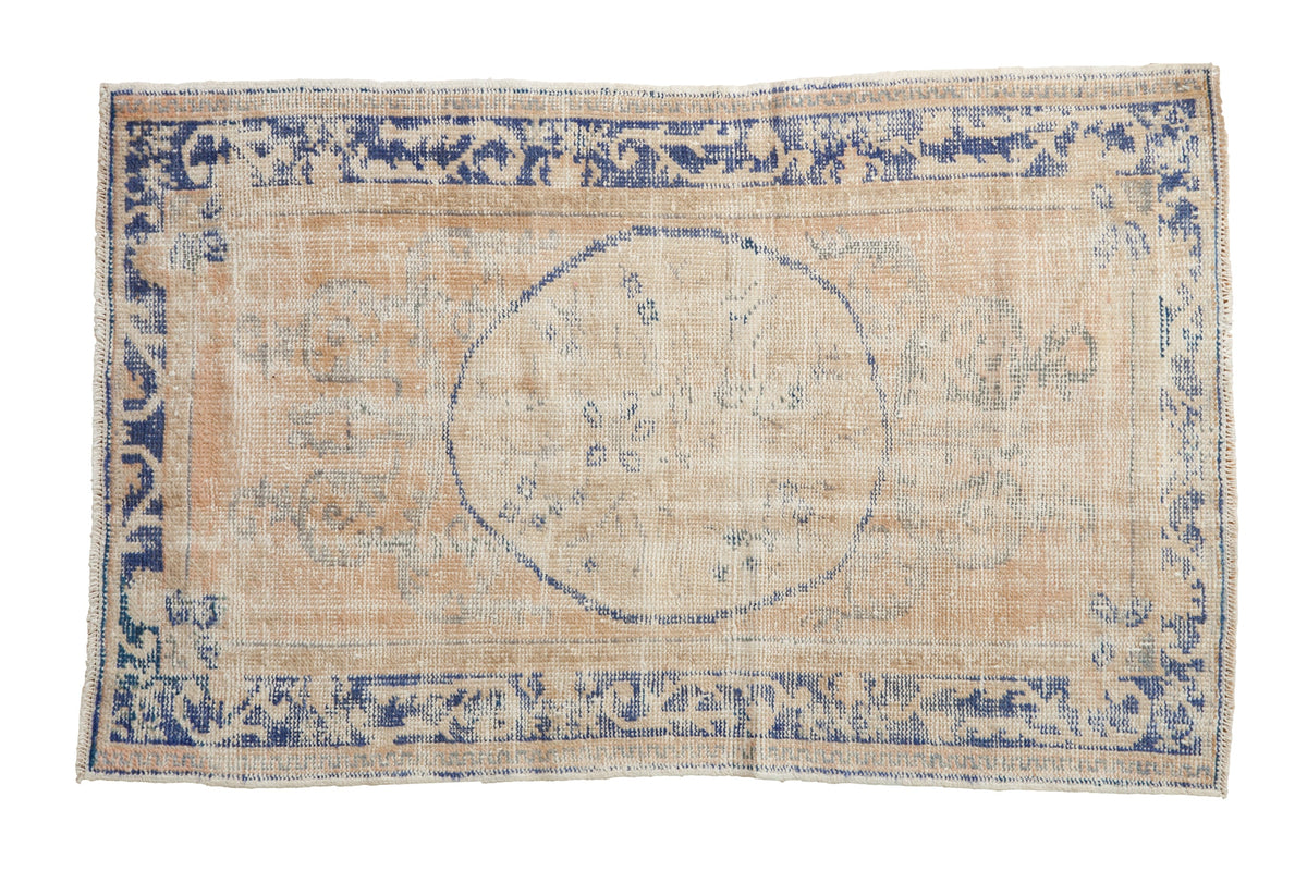 Vintage distressed Oushak rug with a dusty cobalt blue roundel medallion and border on a faded cream field.