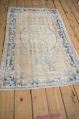 Angled display of a vintage Oushak rug, highlighting the distressed pile and roundel medallion.