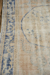 The hand-knotted pile of a vintage Oushak rug showing mostly even wear in cream and dusty blue.