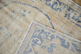 A folded corner showing the hand-knotted back and textured low pile of a distressed Oushak rug.