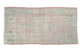 Distressed Oushak rug with faded pale pink, antique ivory, and green trefoil medallion.