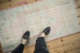 Textured pile of vintage distressed Oushak rug in pale pink, ivory, and jade green.
