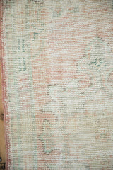 Worn pile texture of distressed vintage Oushak rug in pale pink, ivory, and side selvage.