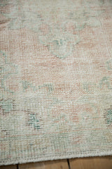 Distressed Oushak rug pile close-up showing foundation wear, pale pink, ivory, green tones.