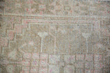 Close-up of distressed Oushak rug pile: worn knot heads, exposed foundation, soft beige, pink, silver.