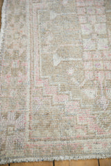 Close-up of distressed Oushak rug pile with knot heads, side selvage, and beige, pink tones.