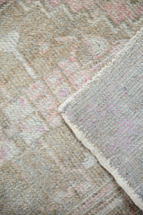 Distressed Oushak rug showcasing worn beige pile with pink tones and gray foundation.