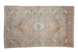 Distressed vintage Oushak rug with concentric medallions in muted rose, bronze, and slate blue.