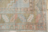 Distressed Oushak rug corner, serrated main border with dusty rose, slate blue, and bronze.