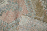 Distressed vintage Oushak rug corner revealing worn pile and hand-knotted foundation.