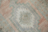 Distressed vintage Oushak rug texture, showing geometric dusty rose and slate blue pattern.