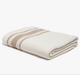 Folded ivory woven tablecloth with tan French stripes showing a detailed herringbone weave.
