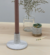 Wide ceramic taper candle holder with a speckled white glaze and a flat, round base.