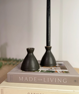 Two handmade matte black ceramic taper holders with speckled glaze, one holding a black candle.