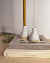 Two speckled white ceramic taper candle holders with natural clay bases.