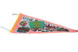 A detailed view of the graphic on a pink felt pennant showing the Wall Drug sign and Mount Rushmore.