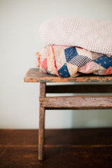 Side view of the primitive stool's leg, showing the chippy turquoise painted texture.