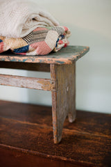 Rustic wooden leg and joinery of a stool with chippy turquoise and white paint.