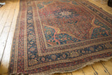 Angled corner view of an antique Persian rug highlighting the intricate spandrels and borders.
