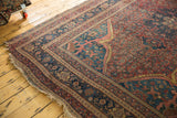 Worn corner and frayed selvage of an antique Persian rug with an ornate spandrel design.