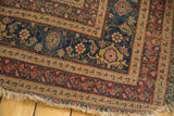 Close-up of the frayed edge and floral border of an antique Persian area rug.