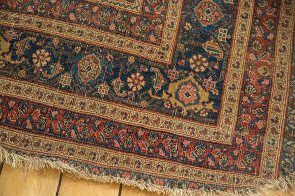 Close-up of the frayed edge and floral border of an antique Persian area rug.