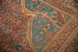 Angled view of an antique Persian rug corner with red and blue floral arabesques.