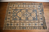 Antique Caucasian rug with a geometric pattern in a neutral palette of tan, blue, and dark brown.