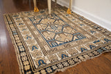 Angled view of a supple antique Caucasian rug, showing its neutral geometric pattern and characterful, worn ends.