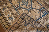 Folded corner of an antique Caucasian rug showing its hand-knotted back and frayed, timeworn edge.